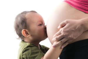Baby kissing pregnant woman's belly