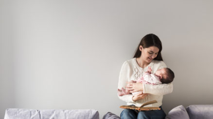 Woman With Book Holding Newborn Baby