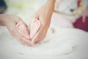 Newborn Baby's Feet In The Mother's Hands